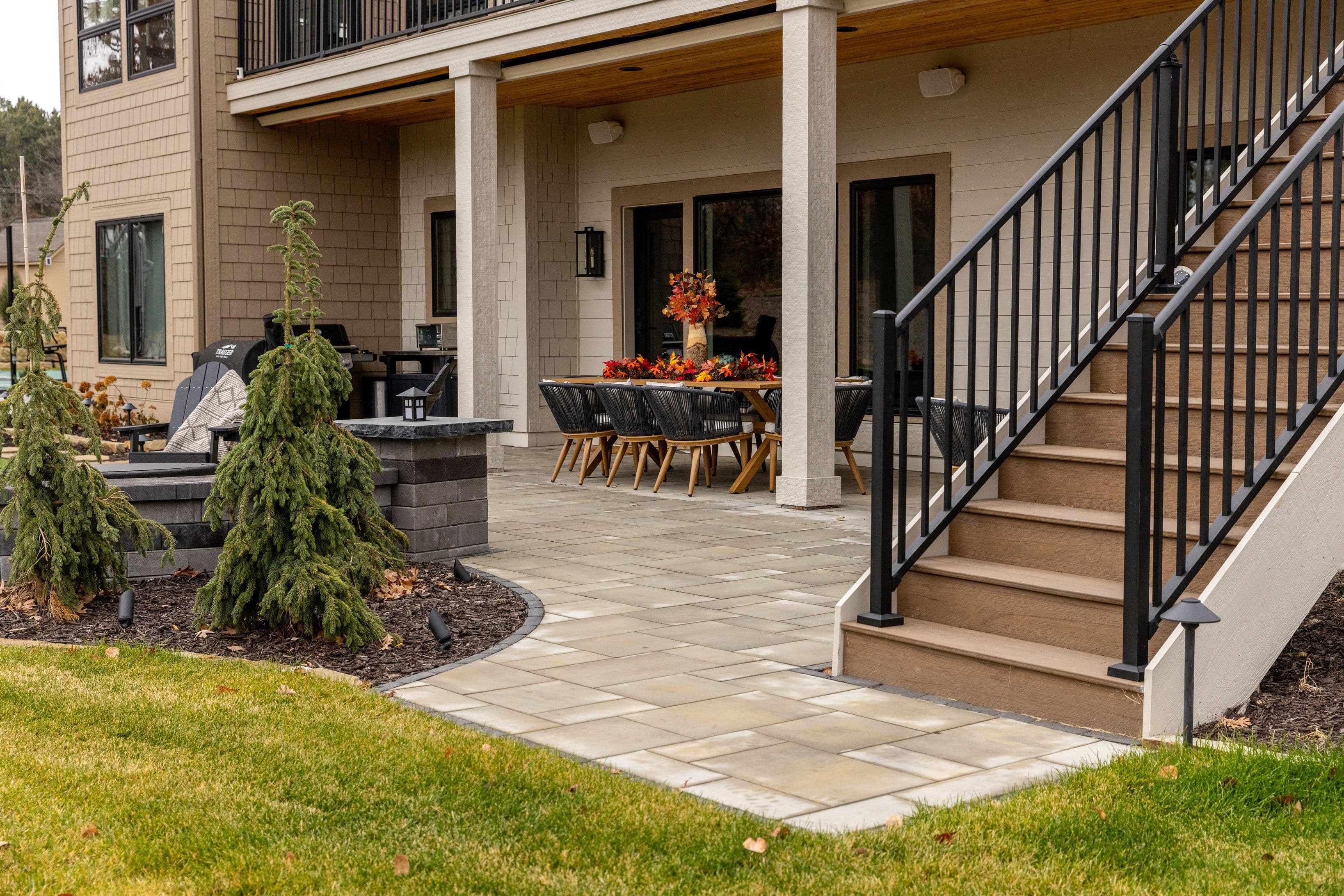 Backyard patio with dining table, grill, and landscaped stairs in a modern home setting.
