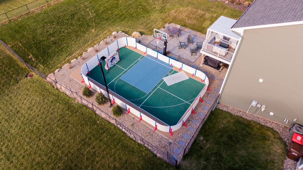 Aerial view of a home basketball court surrounded by landscaping and a patio area.