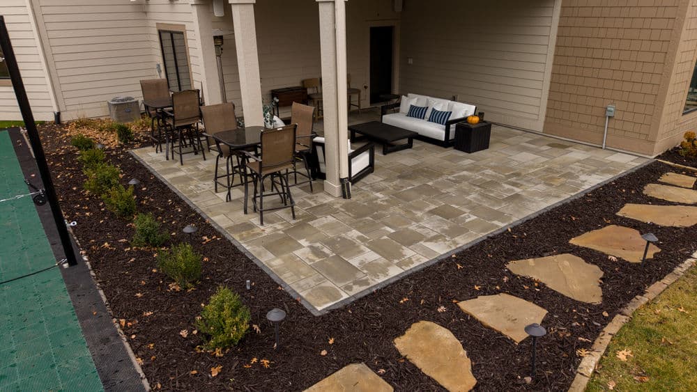 Cozy outdoor patio with seating, pavers, and landscaping elements in a residential setting.