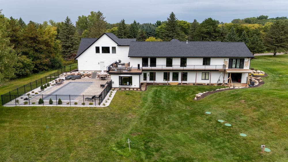 Aerial view of a modern home with a patio, pool area, and landscaped yard.