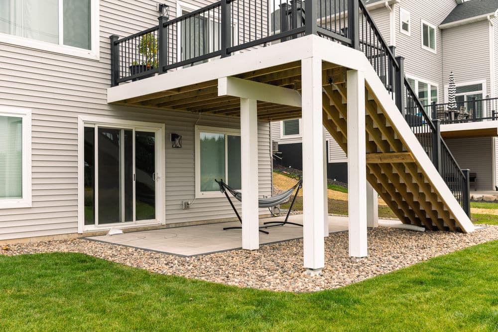 Home exterior featuring a patio under a deck with a hammock and landscaping.
