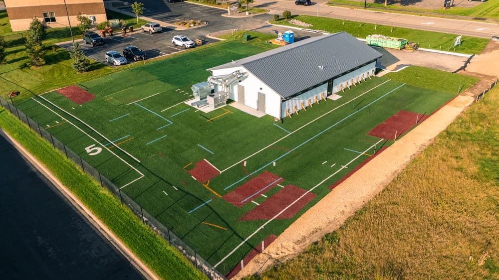 Aerial view of a facility with turf fields and training equipment, surrounded by landscaping.